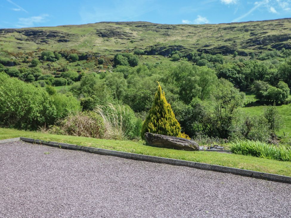 An outdoor area with gravel, trees, and hills at The Skating Rock in Bunane near Kenmare, County Kerry