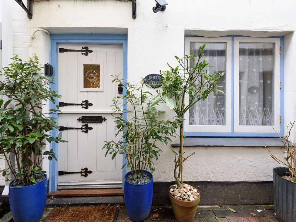 An entrance door with plants and a sign at Dolls Cottage in Looe