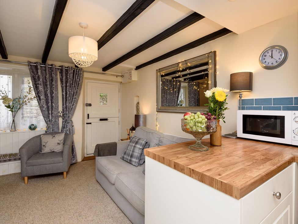 A living room with a sofa and armchair at Dolls Cottage in Looe