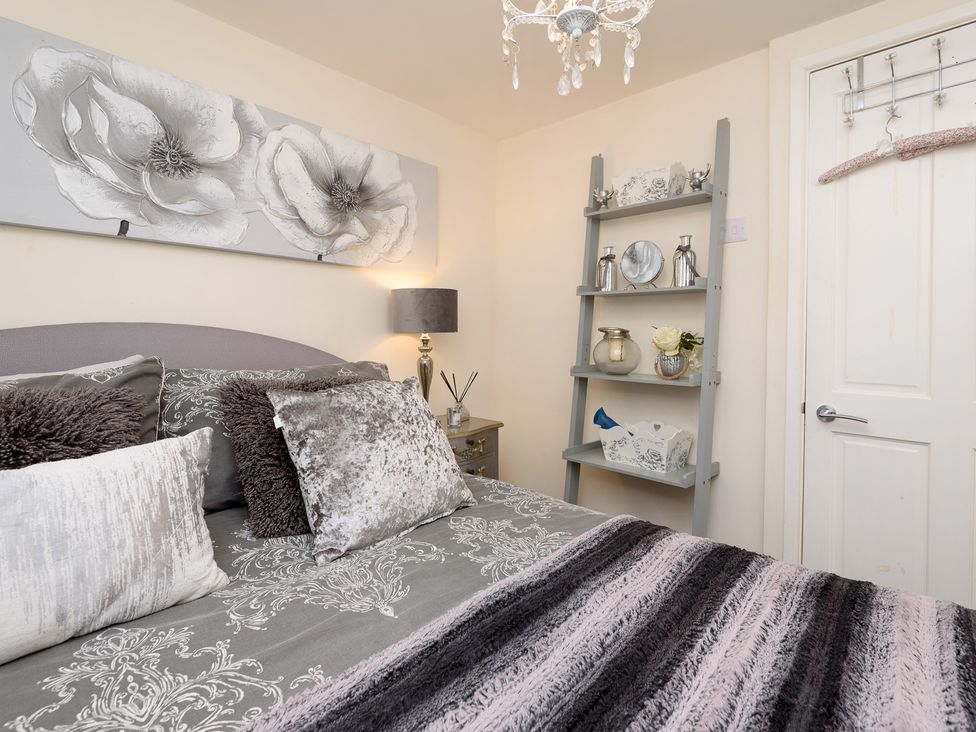 A bedroom with a bed and decorative shelf at Dolls Cottage in Looe