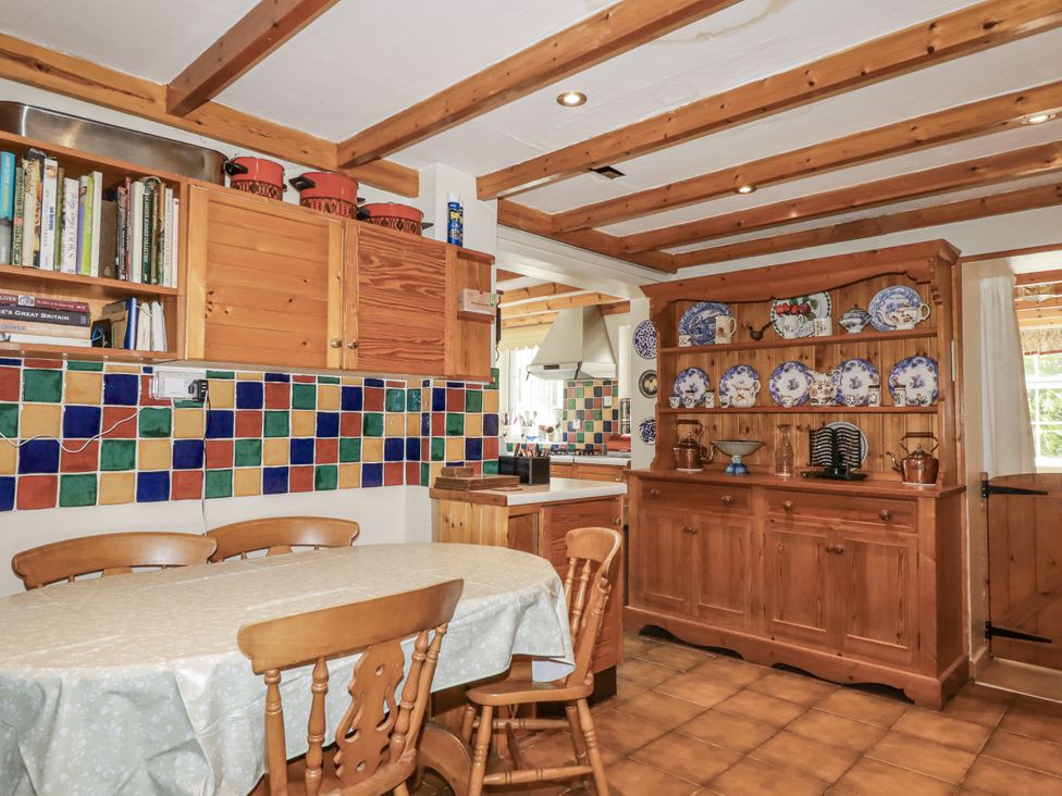 A kitchen with a dining table and wooden cabinets at Temple House in Goonhavern