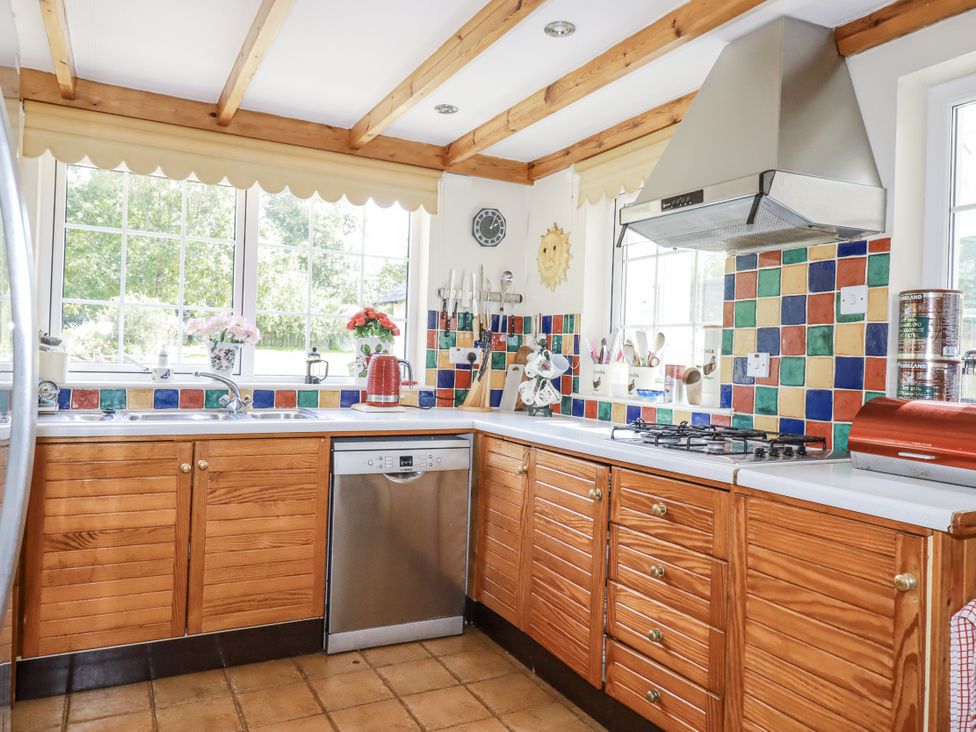 A kitchen with wooden cabinets and colorful tiles at Temple House in Goonhavern