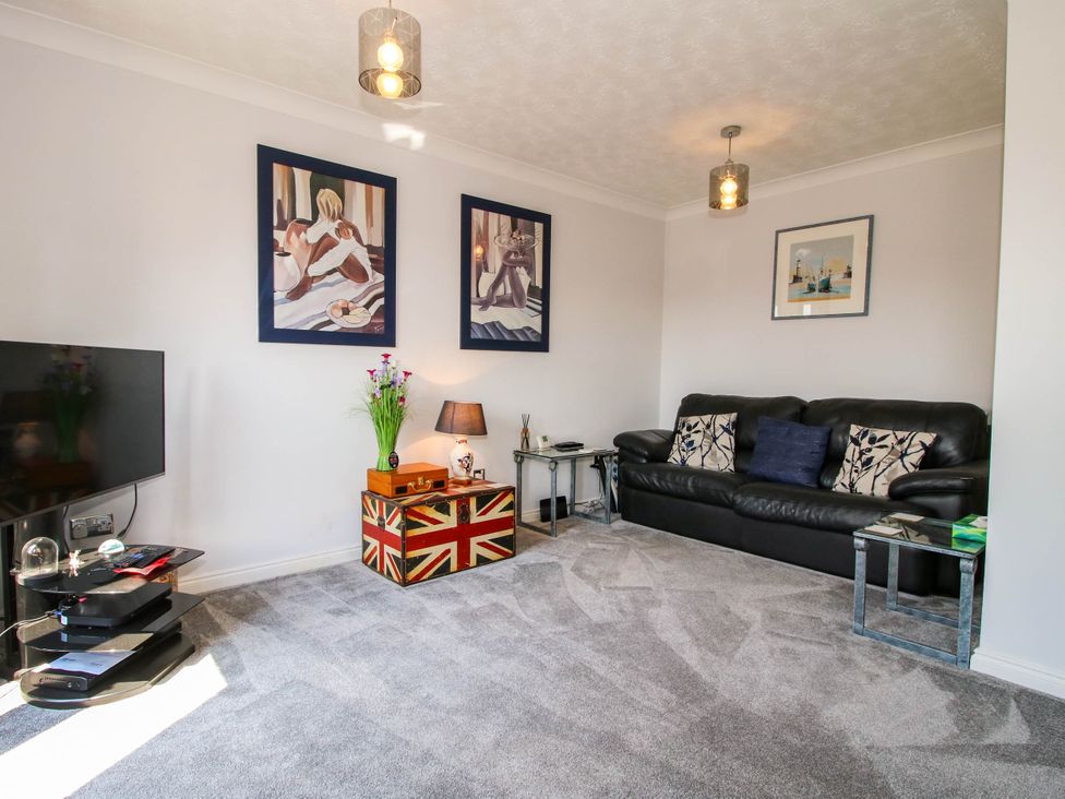 A living room with a black leather sofa and framed art on the walls at 63 Severn Street in Bridgnorth