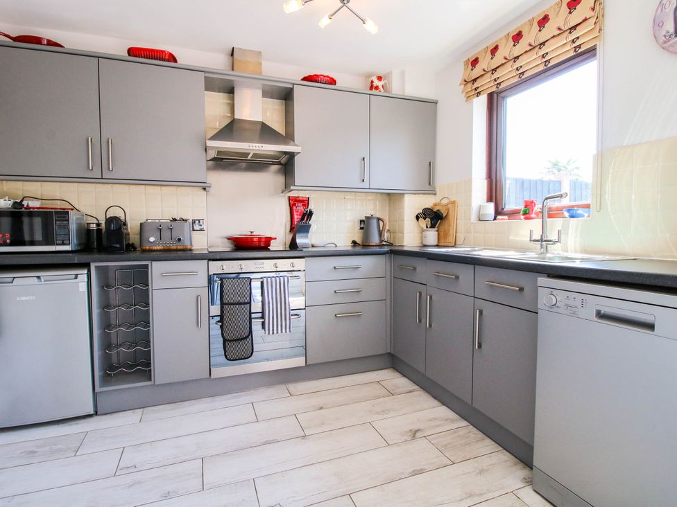 A kitchen with gray cabinets appliances and a window with floral blinds at 63 Severn Street in Bridgnorth