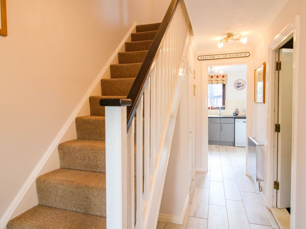 A hallway with carpeted stairs on the left and a kitchen visible at the end at 63 Severn Street Bridgnorth