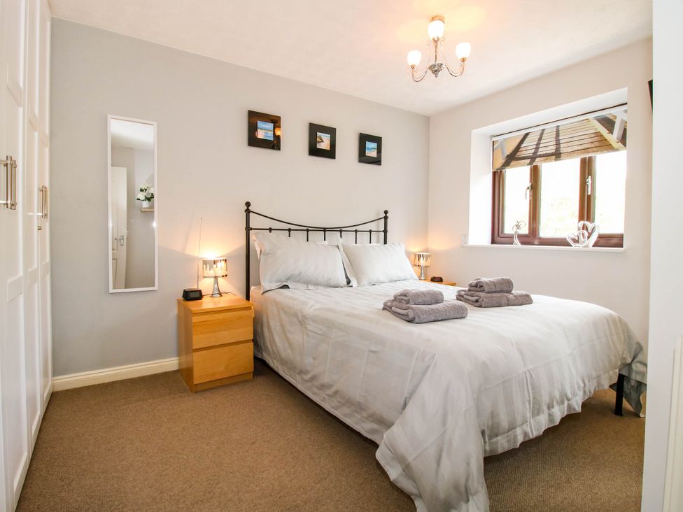 A bedroom with a double bed white bedding two bedside tables with lamps a window and a wall mirror at 63 Severn Street in Bridgnorth