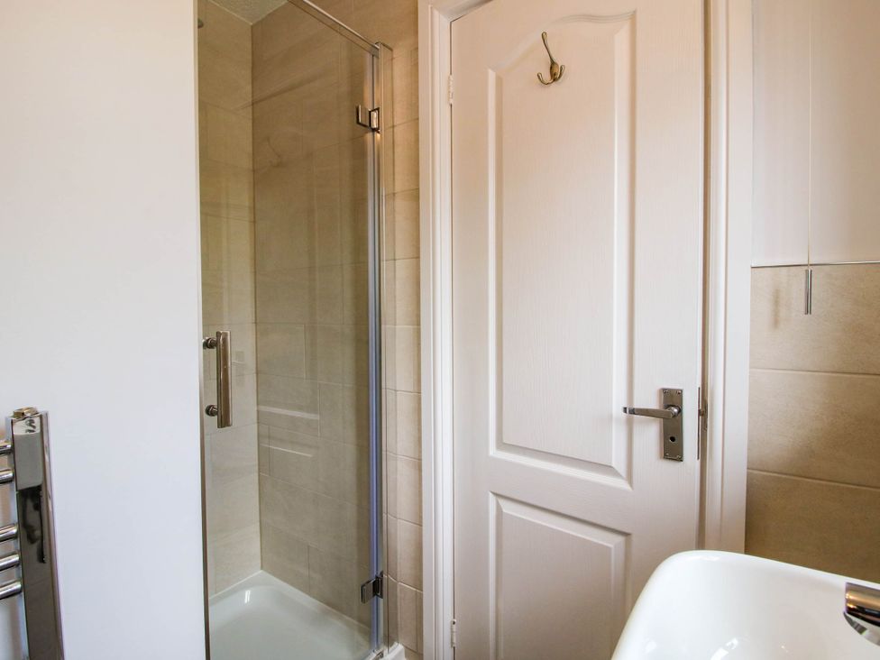 A bathroom with a glass shower enclosure a white door and part of a white sink at 63 Severn Street in Bridgnorth
