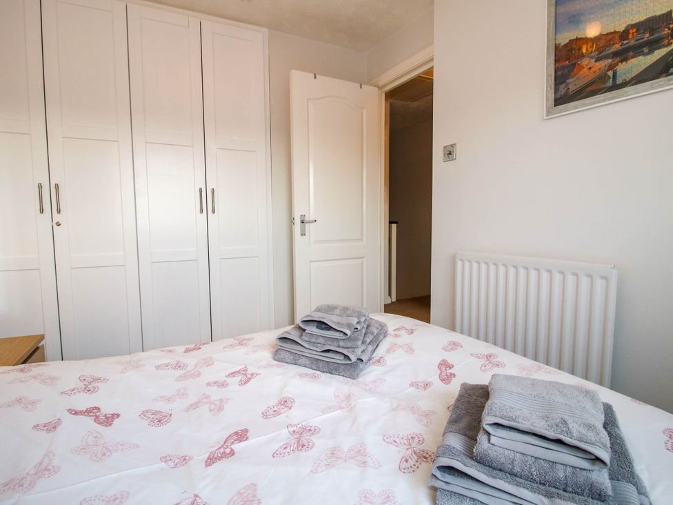 A bedroom with a bed featuring butterfly patterned bedding folded towels on the bed a white wardrobe a white door and a radiator on the wall at 63 Severn Street Bridgnorth