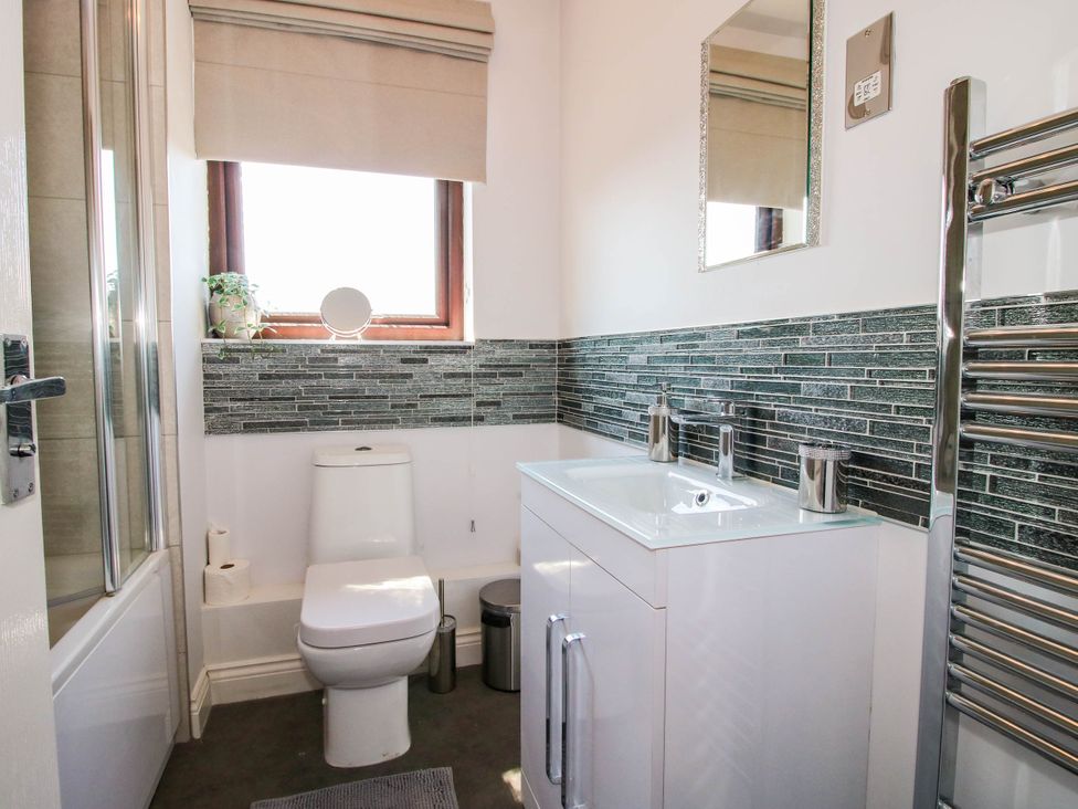 A bathroom with a toilet sink cabinet mirror window and towel radiator at 63 Severn Street Bridgnorth