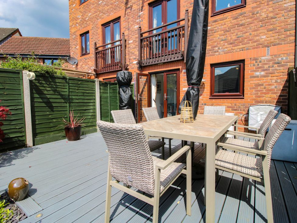 An outdoor patio with a dining table and six wicker chairs on a wooden deck at 63 Severn Street in Bridgnorth