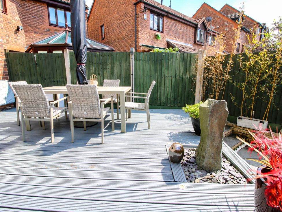 An outdoor patio with a dining table and chairs next to a tall stone feature and plants at 63 Severn Street Bridgnorth