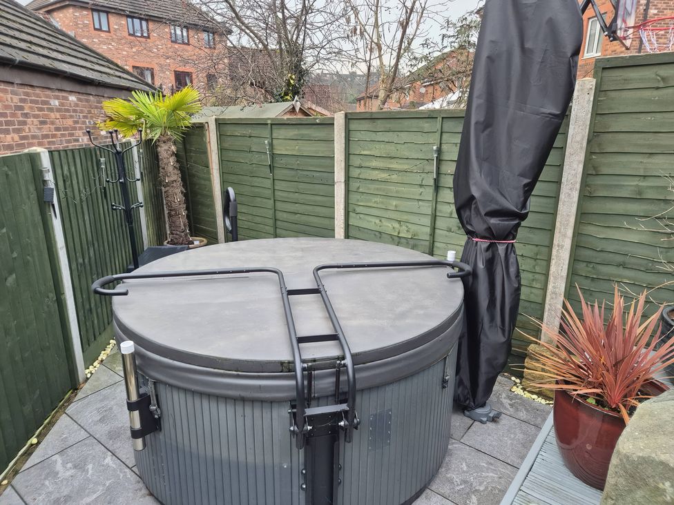 A hot tub with a palm tree and fencing in the garden at 63 Severn Street in Bridgnorth