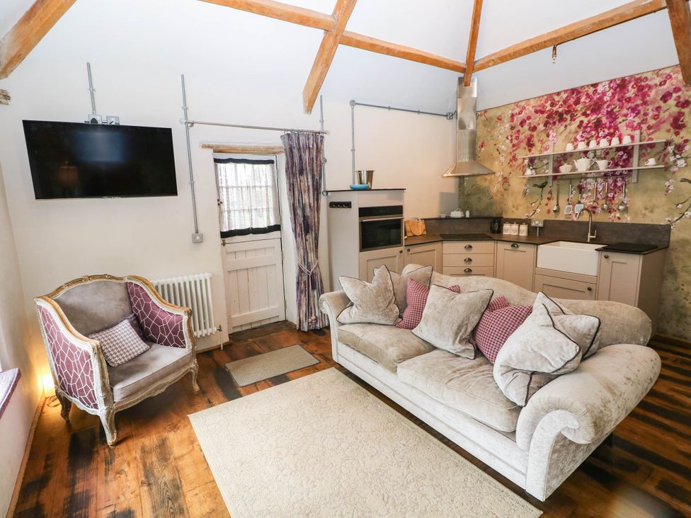 A living room with a sofa and kitchen unit at The Apple Store at Gileston Manor Gileston near St Athan