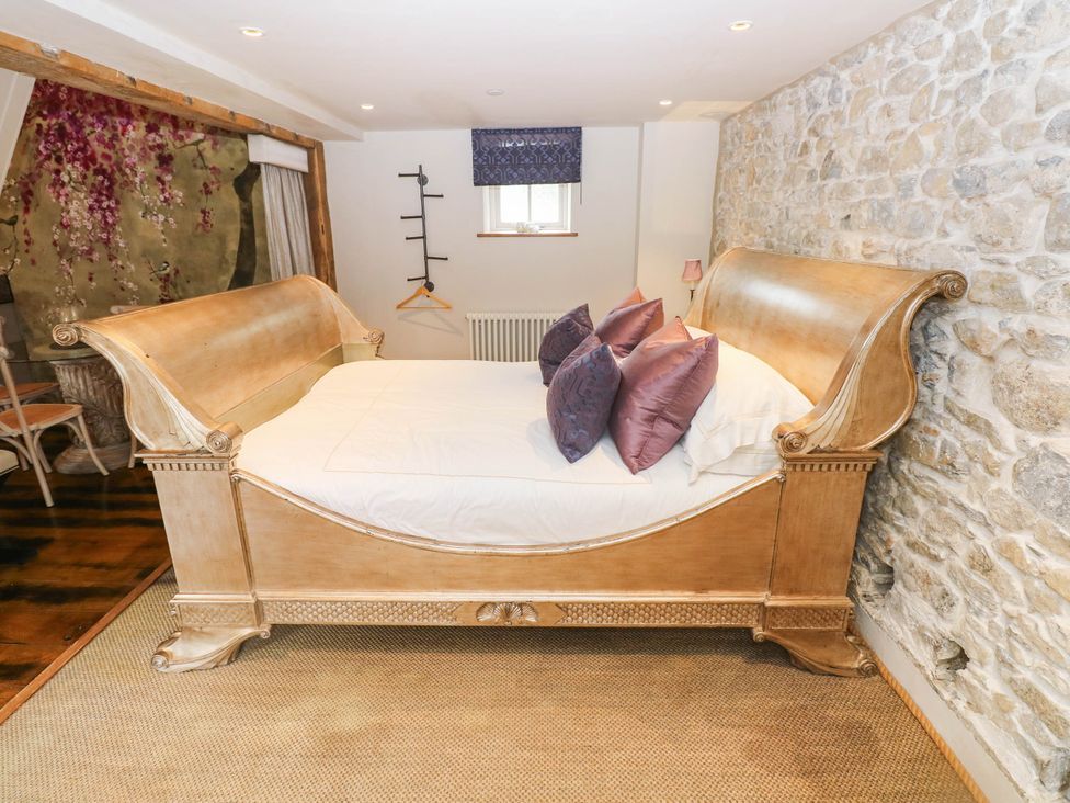 A bedroom with a wooden bed and decorative pillows at The Apple Store at Gileston Manor
