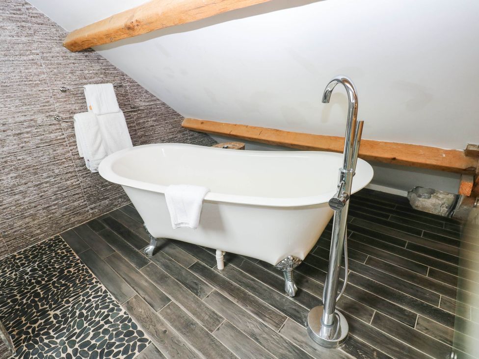 A bathroom with a bathtub and towels at The Apple Store at Gileston Manor, Gileston near St Athan