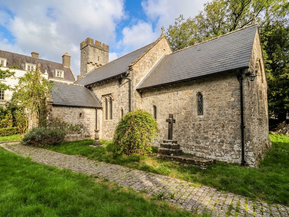 A church with a stone facade and a cross in the garden at The Apple Store at Gileston Manor Gileston near St Athan