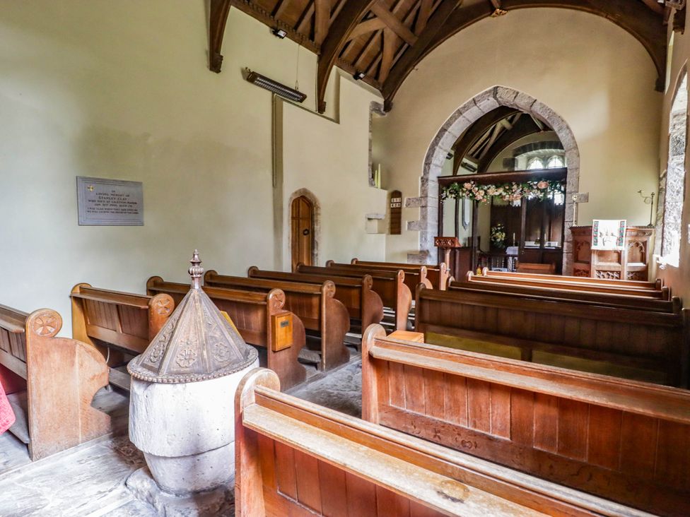 A church with wooden pews and a font at The Apple Store at Gileston Manor, Gileston near St Athan