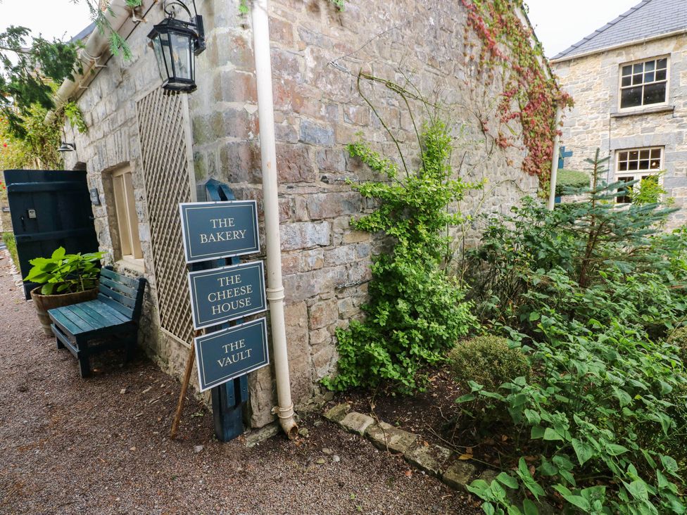 An outdoor area with signs indicating The Bakery, The Cheese House, and The Vault at The Apple Store at Gileston Manor Gileston near St Athan