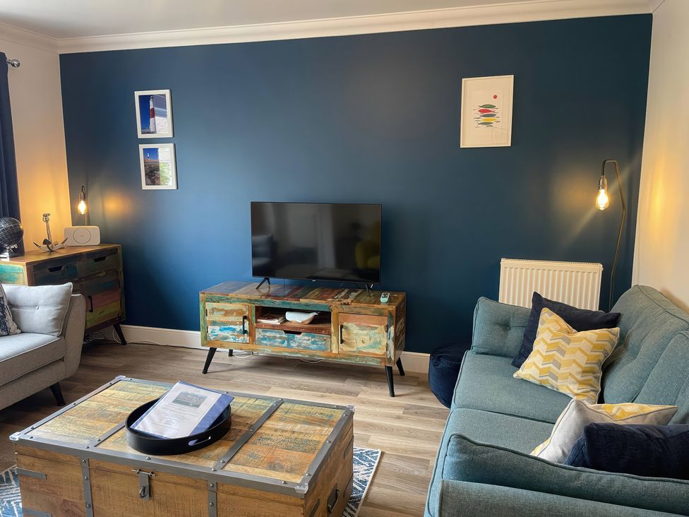 A living room with a television and sofa at Plain Sailing in Weymouth