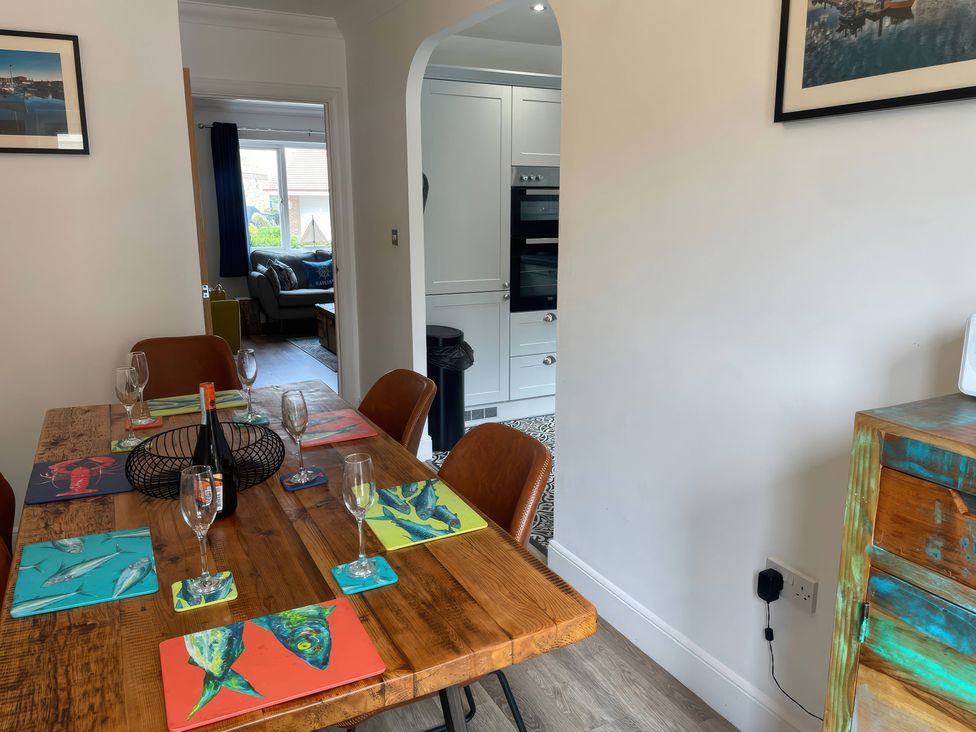 A dining room with a wooden table and chairs at Plain Sailing in Weymouth