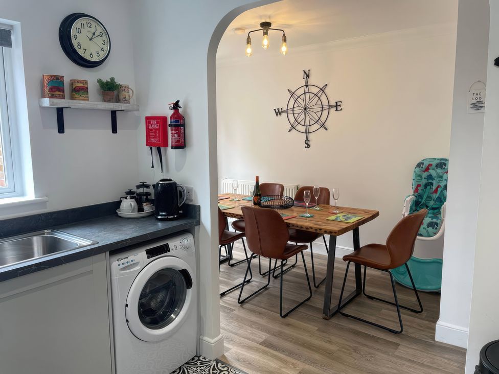 A kitchen with a washing machine and dining table at Plain Sailing in Weymouth