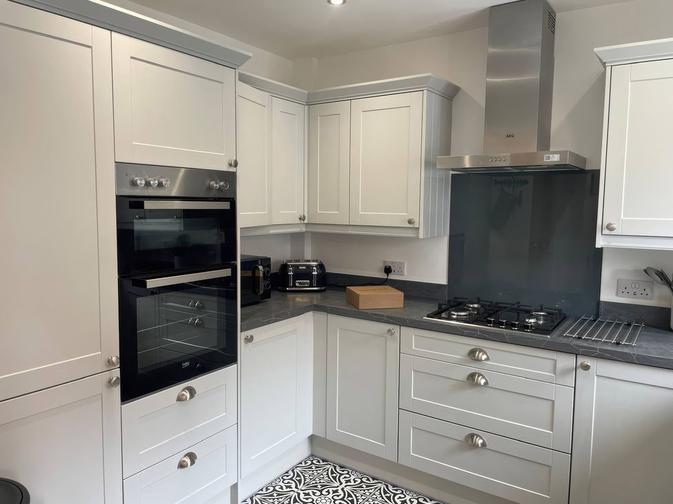 A kitchen with cabinets, an oven, microwave, and a gas stove at Plain Sailing in Weymouth