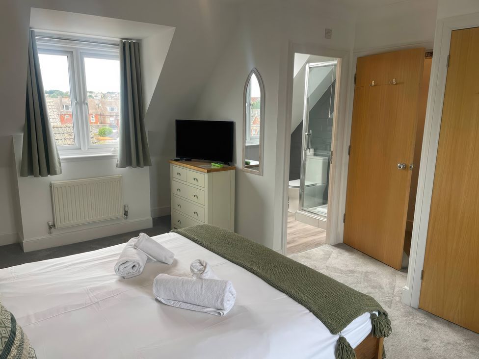 A bedroom with a bed, television, and en-suite bathroom at Plain Sailing in Weymouth