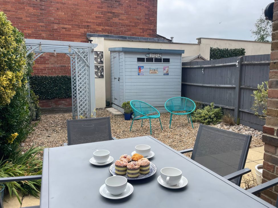 A garden with a table and chairs, shed and cupcakes at Plain Sailing in Weymouth