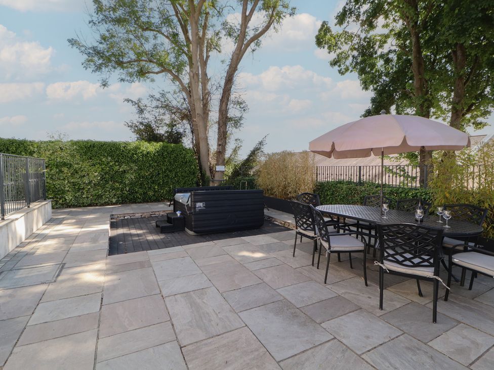 An outdoor area with a hot tub and dining table at Ingleborough Kirkby Lonsdale