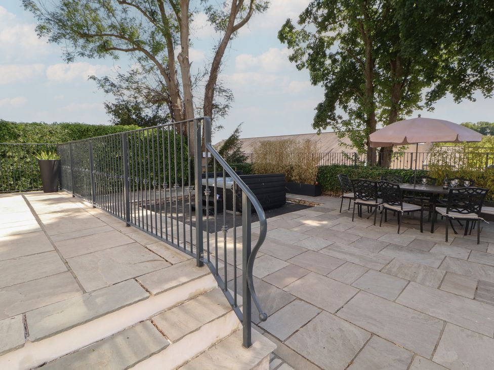 A outdoor patio with a table and chairs under an umbrella at Ingleborough, Kirkby Lonsdale