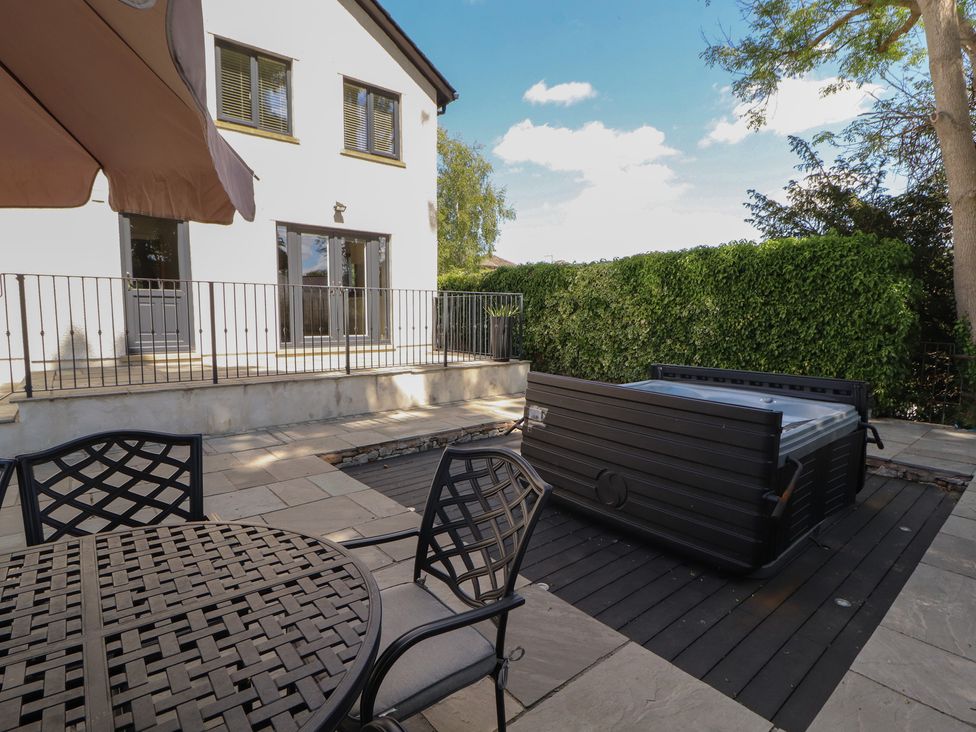 An outdoor patio with a table and chairs near a hot tub at Ingleborough Kirkby Lonsdale