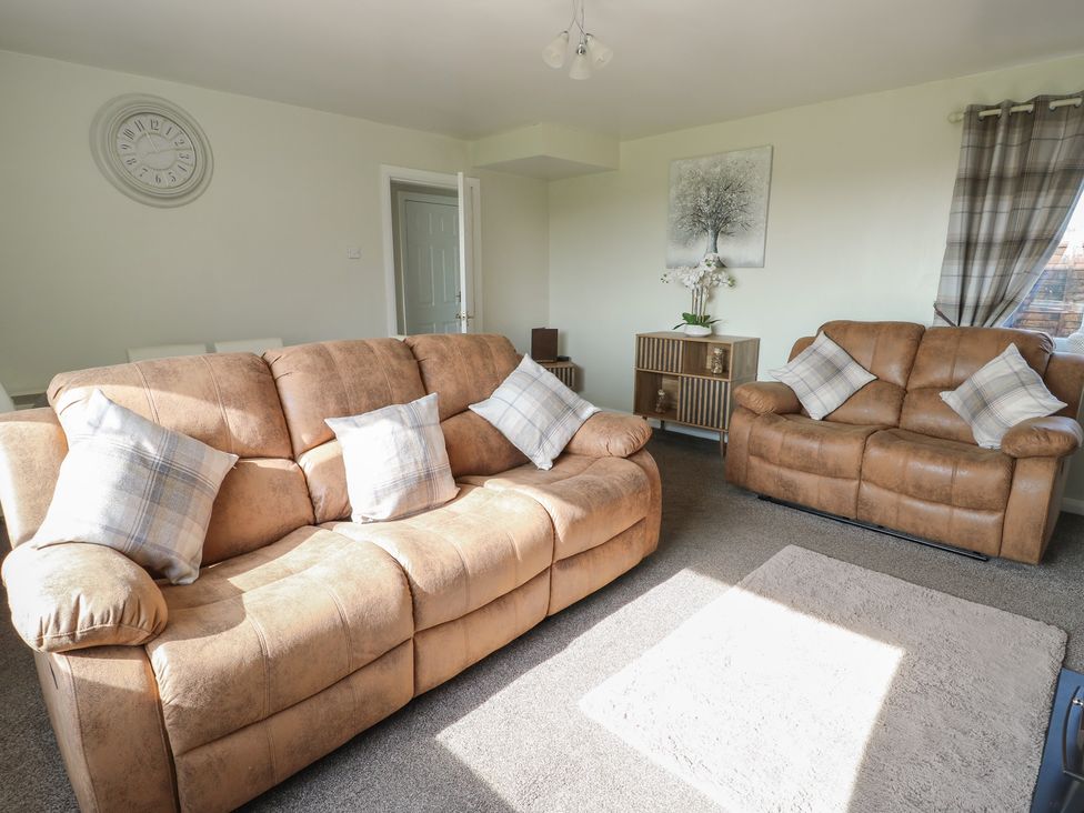 A living room with sofas and a clock at Pentre Iago in Rhoscolyn