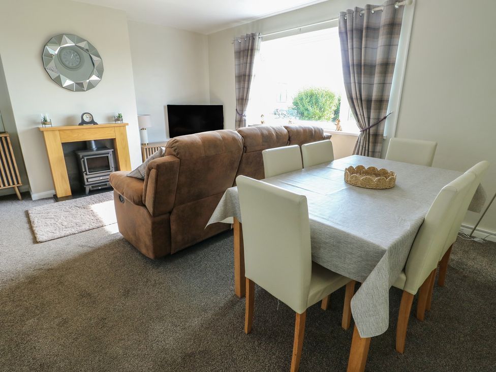 A living room with a sofa and dining table at Pentre Iago Rhoscolyn