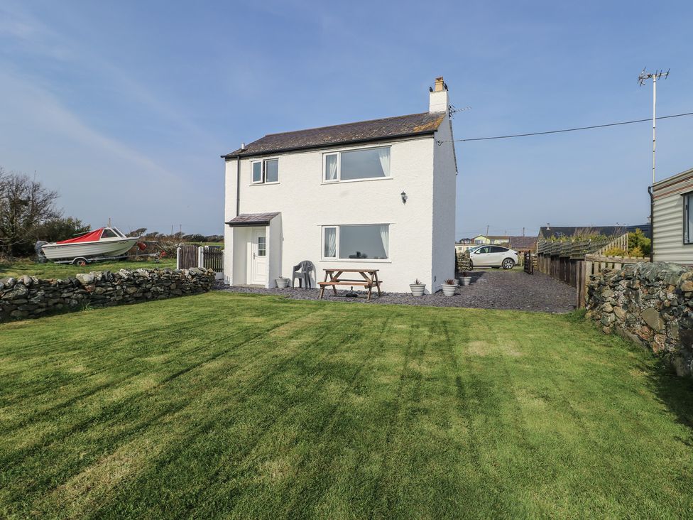 A two-story house with windows and a patio table at Pentre Iago in Rhoscolyn