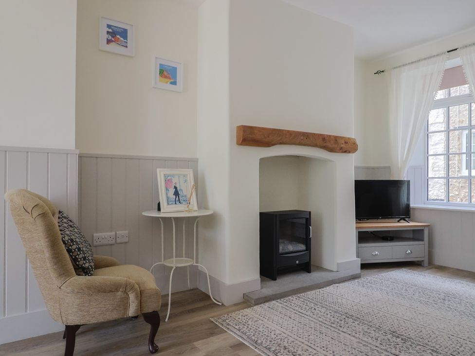 A living room with an armchair and fireplace at Belfry Cottage in Colyton