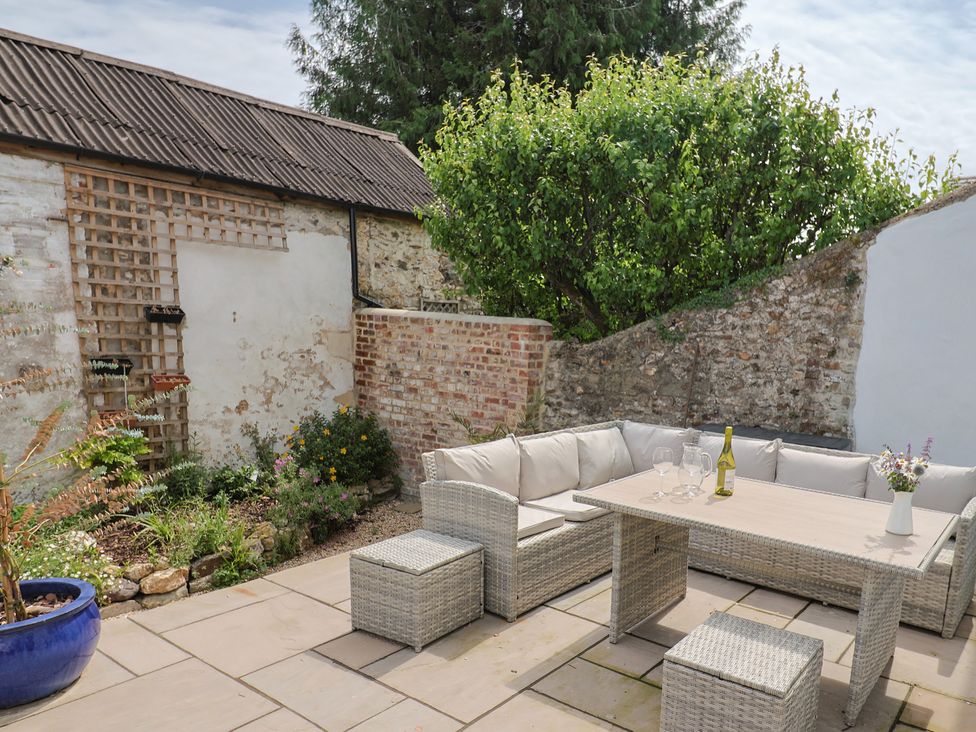 An outdoor garden with seating and a coffee table at Belfry Cottage Colyton