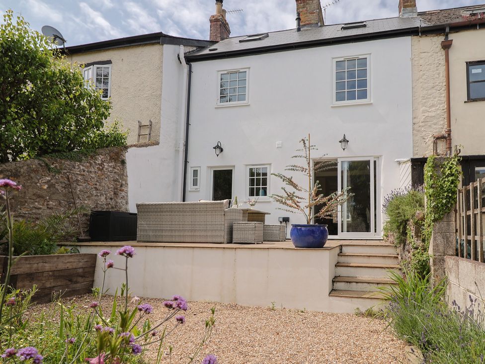 A garden with a seating area and steps at Belfry Cottage in Colyton