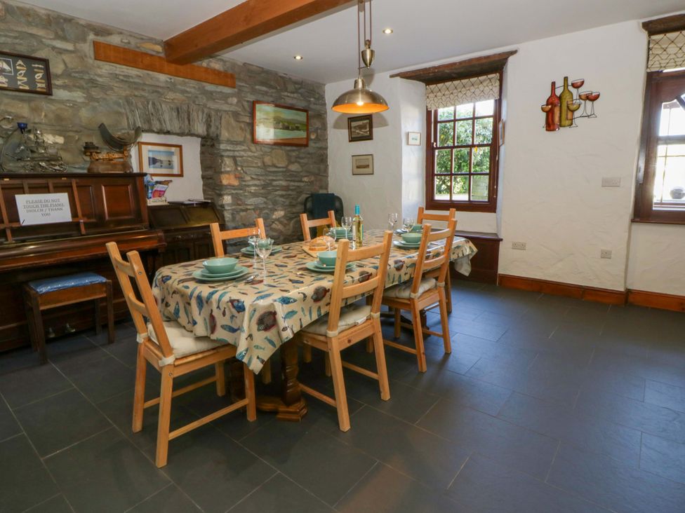A dining room with a table set and a piano at Parrog Stores near Newport, Pembrokeshire