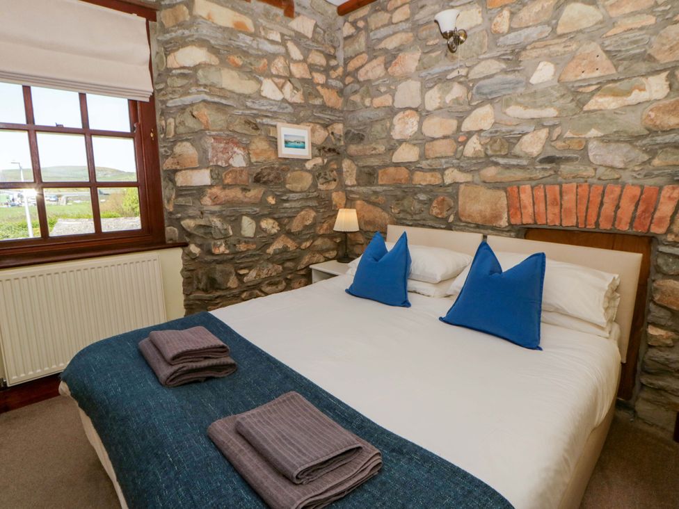 A bedroom with a bed and stone walls at Parrog Stores Parrog near Newport, Pembrokeshire