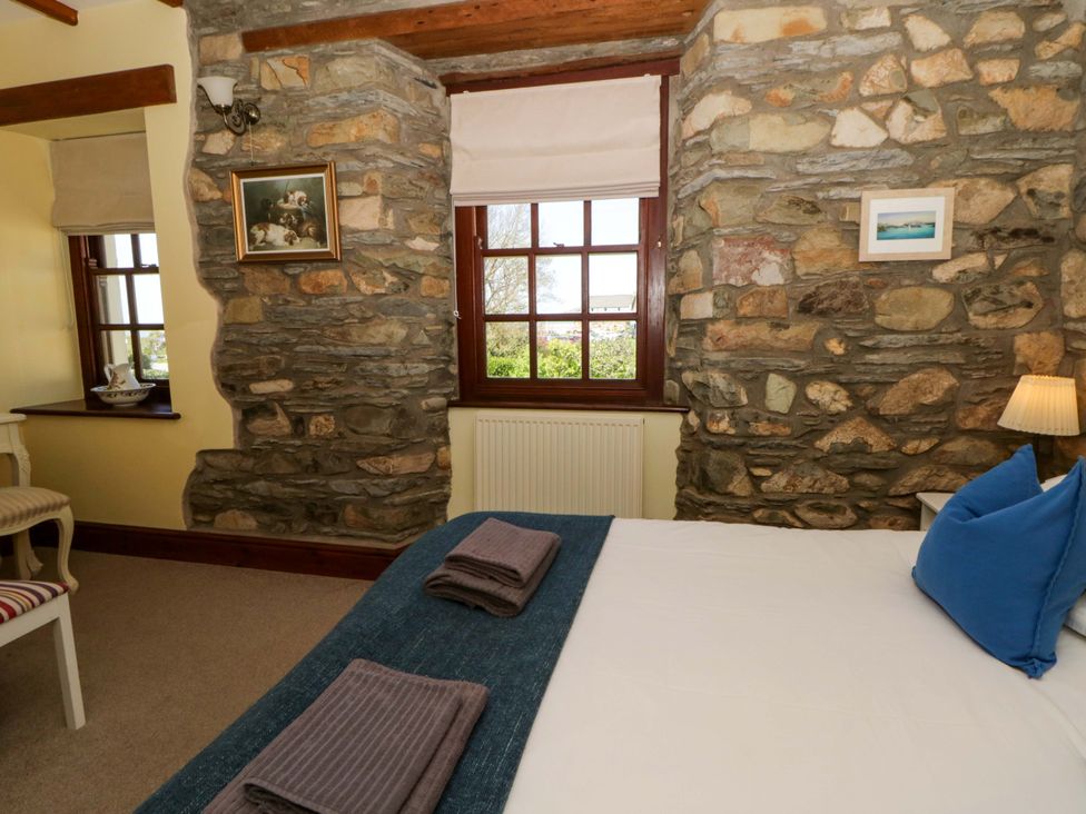A bedroom with stone walls and windows at Parrog Stores in Parrog near Newport, Pembrokeshire