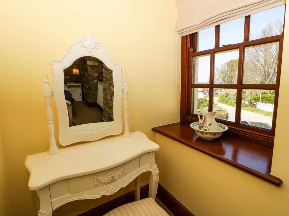 A dressing table with a mirror and a vase on the windowsill at Parrog Stores Parrog near Newport, Pembrokeshire