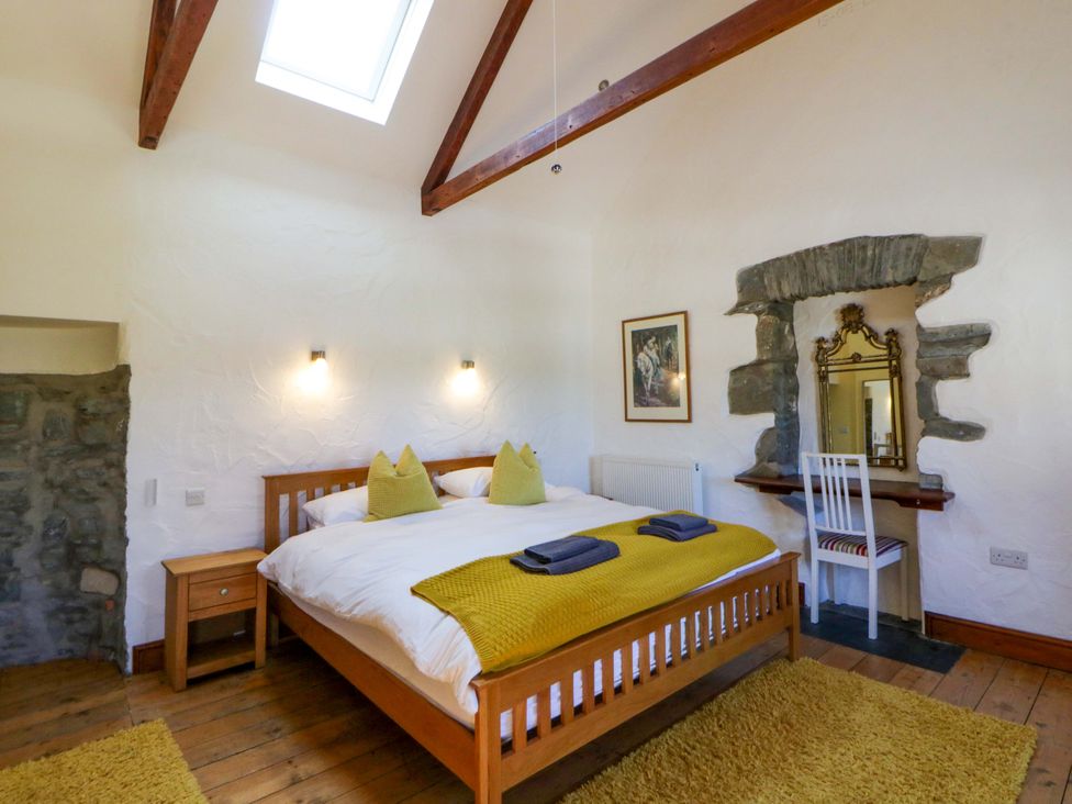 A bedroom with a bed and a mirror at Parrog Stores in Parrog near Newport, Pembrokeshire