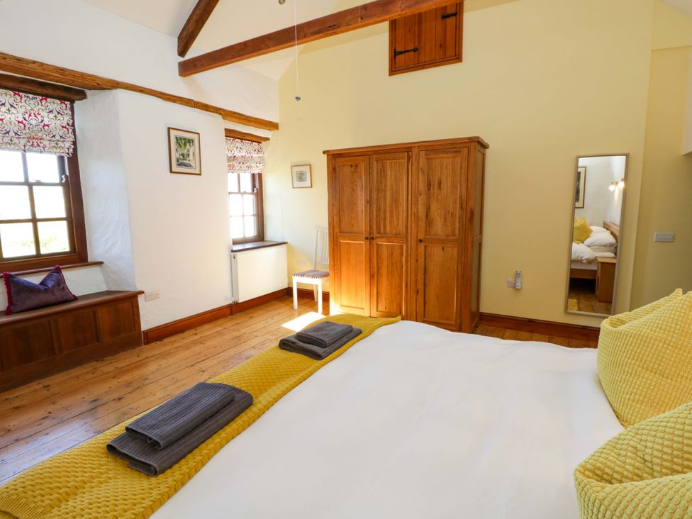 A bedroom with a bed and wooden wardrobe at Parrog Stores near Newport, Pembrokeshire