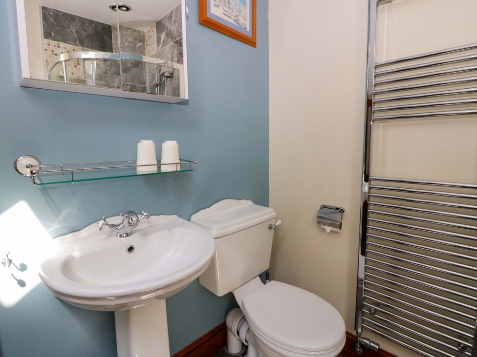 A bathroom with sink, toilet, towel rail and mirror at Parrog Stores in Parrog near Newport, Pembrokeshire