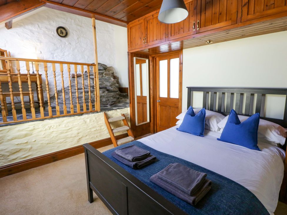 A bedroom with a bed and wooden railing at Parrog Stores in Parrog near Newport, Pembrokeshire