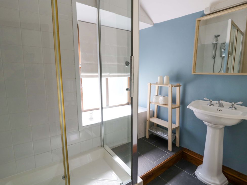 A bathroom with a shower, sink, and shelves at Parrog Stores Parrog near Newport, Pembrokeshire