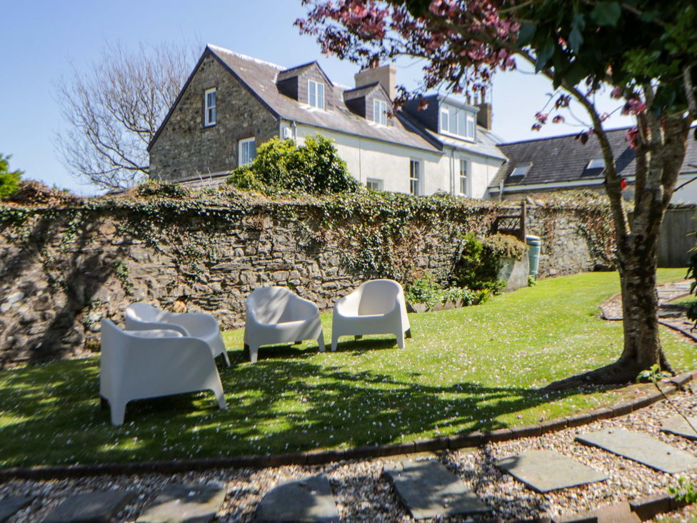 A garden with chairs and a stone wall at Parrog Stores in Parrog near Newport, Pembrokeshire