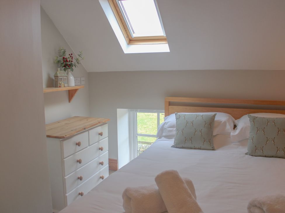 A bedroom with a bed and dresser at School House Cottage in Newtown near Longnor