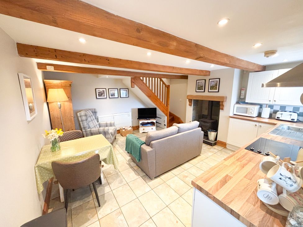 A living room with a sofa and kitchen area at School House Cottage Newtown near Longnor
