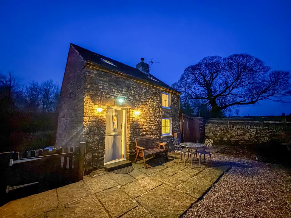An outdoor view of a cottage with table and chairs at School House Cottage Newtown near Longnor